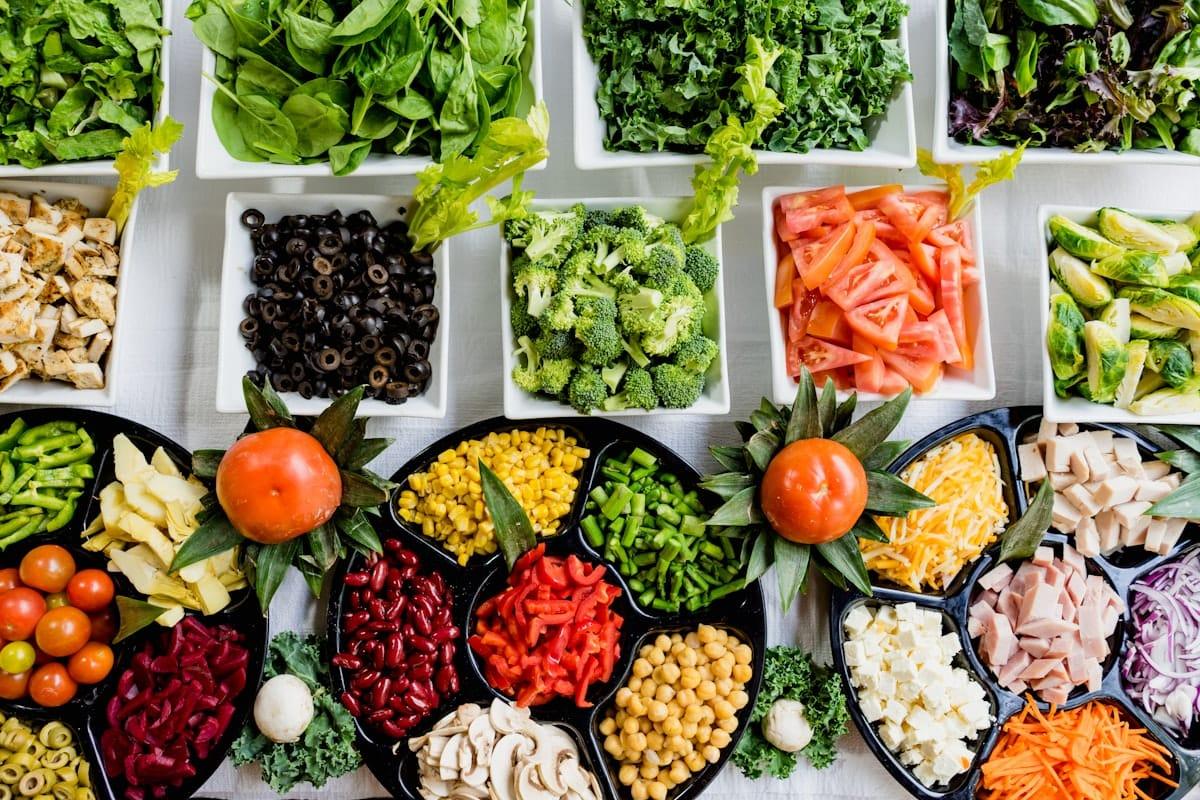 Buffet de légumes frais et variés vu de dessus, évoquant une alimentation saine à la cantine