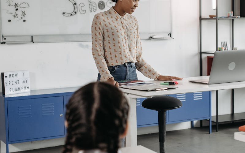 Enseignante devant son bureau préparant la rentrée dans une salle de classe